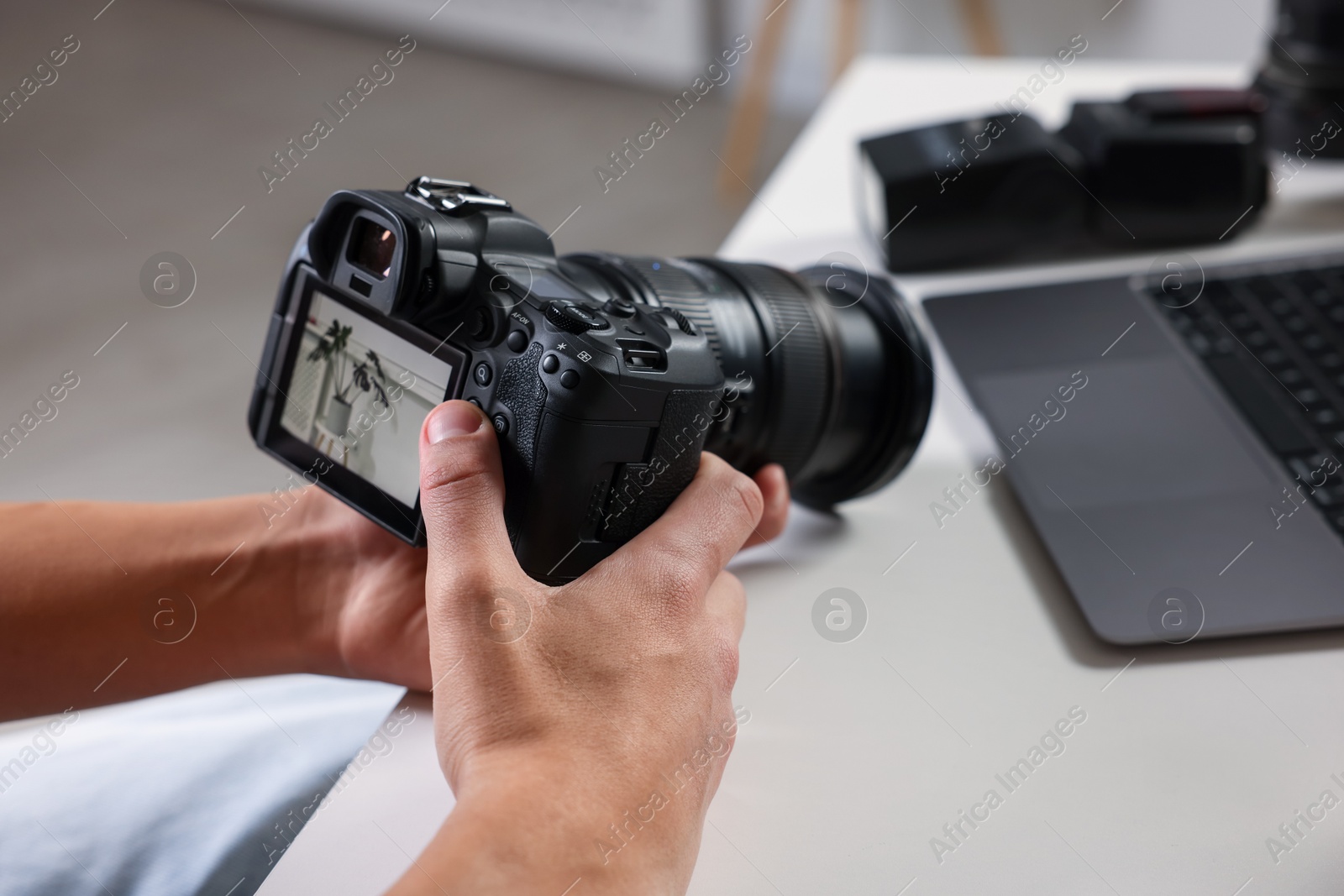 Photo of Photographer with professional camera at white desk indoors, closeup