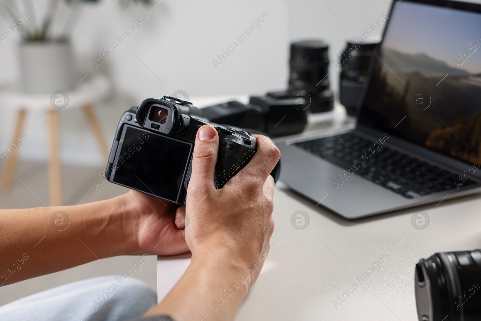 Photo of Photographer with professional camera at white desk indoors, closeup