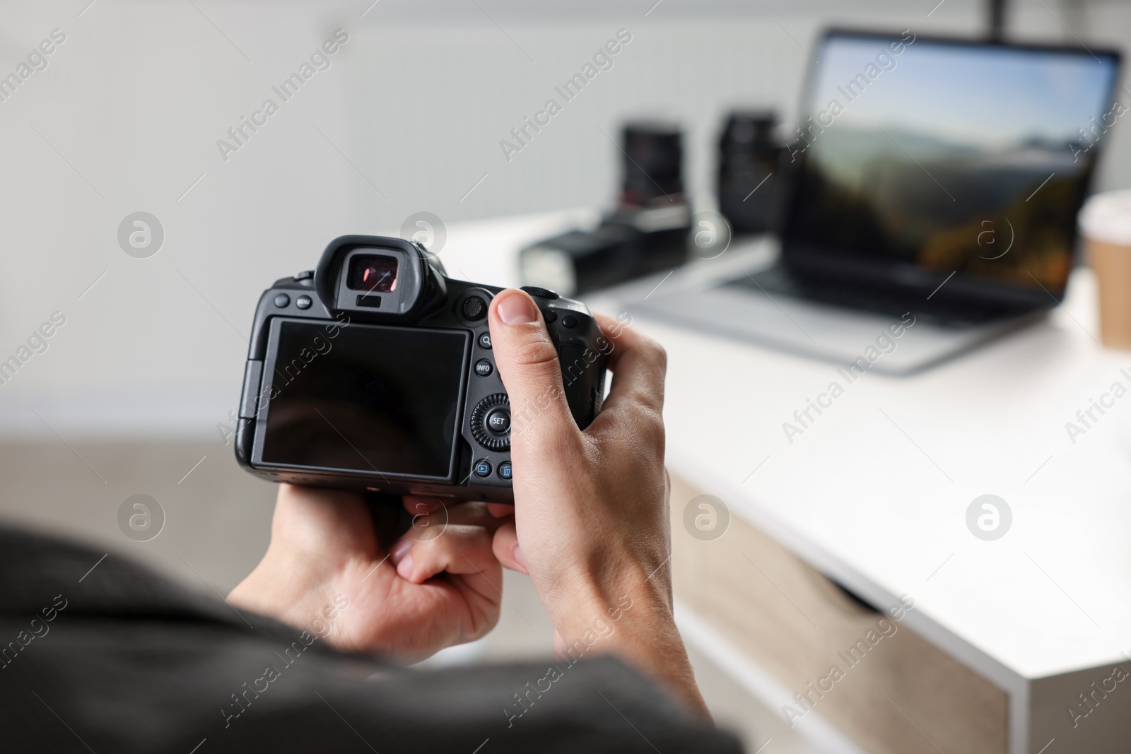 Photo of Photographer with professional camera at white desk indoors, closeup