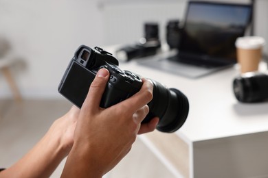 Photo of Photographer with professional camera at white desk indoors, closeup