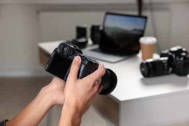 Photo of Photographer with professional camera at white desk indoors, closeup