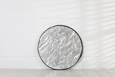 Photo of Professional reflector on floor near white wall. Photo studio equipment