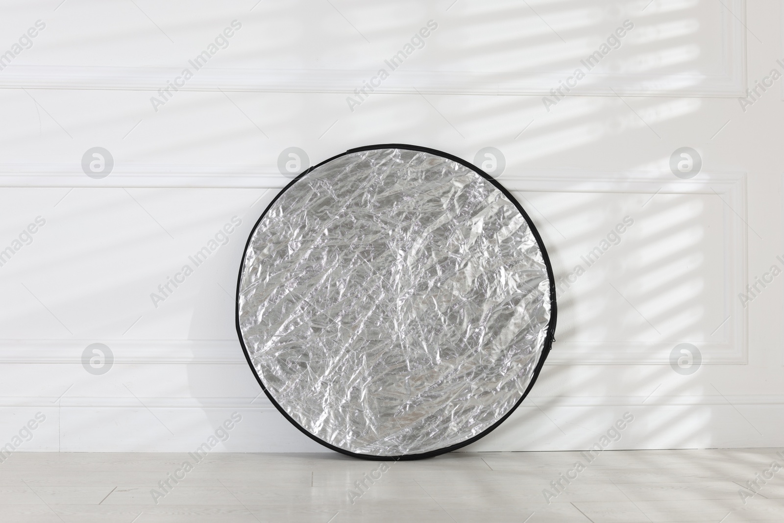 Photo of Professional reflector on floor near white wall. Photo studio equipment