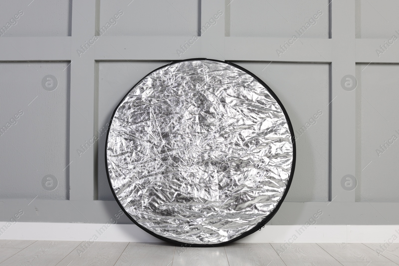 Photo of Professional reflector on floor near grey wall. Photo studio equipment