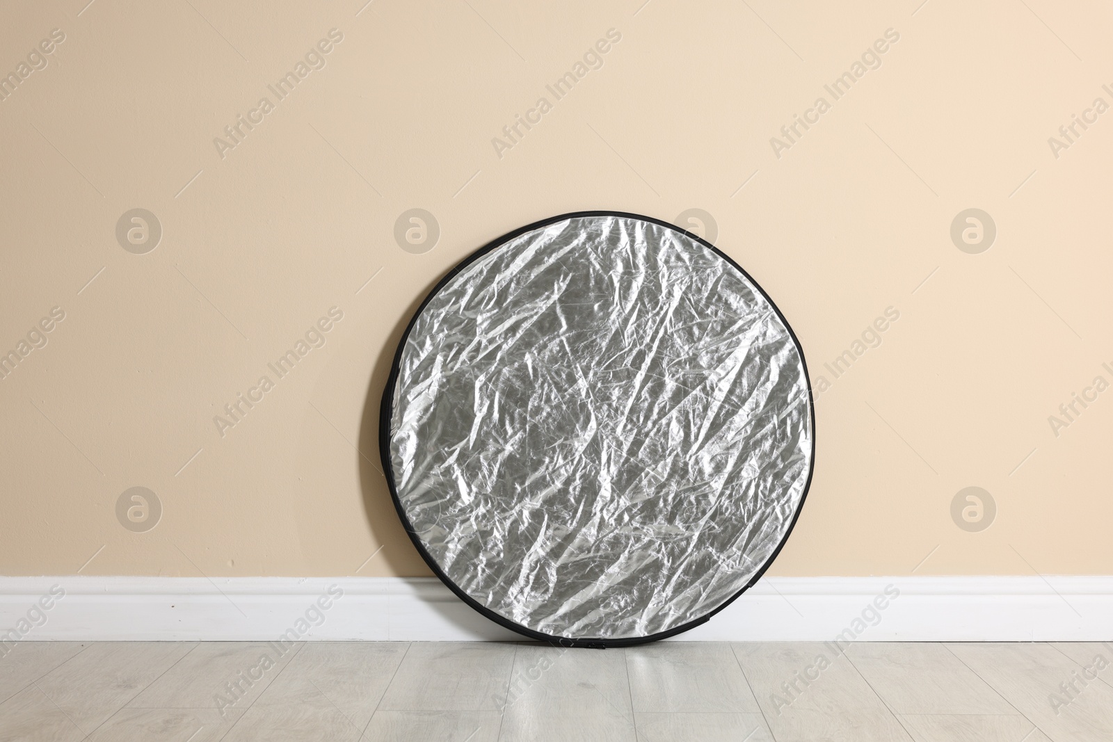 Photo of Professional reflector on floor near beige wall. Photo studio equipment