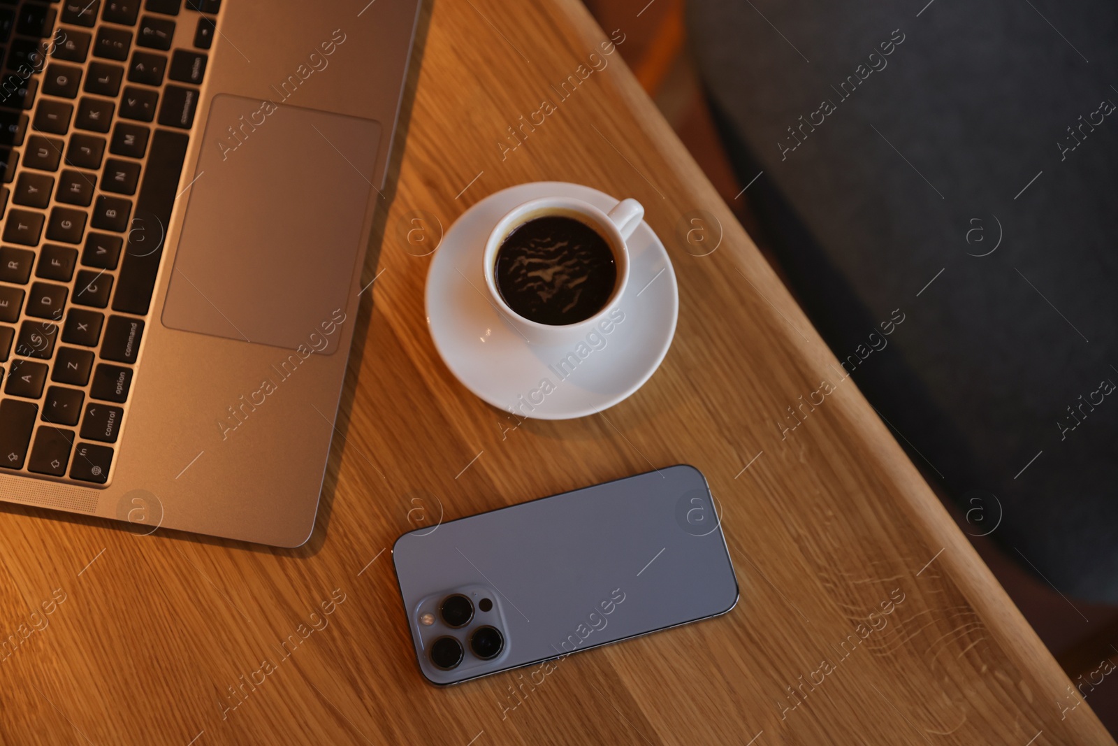 Photo of Laptop, cup of coffee and smartphone on wooden table in cafe, above view