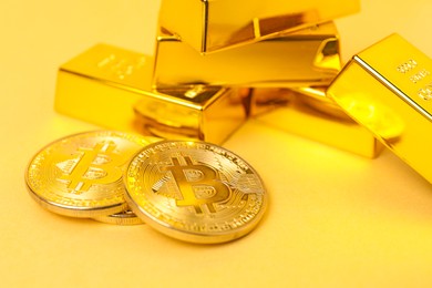 Photo of Gold bars and coins on pale yellow background, closeup