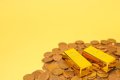 Photo of Gold bars and coins on pale yellow background, closeup. Space for text