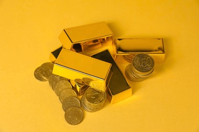 Photo of Gold bars and coins on golden background, above view