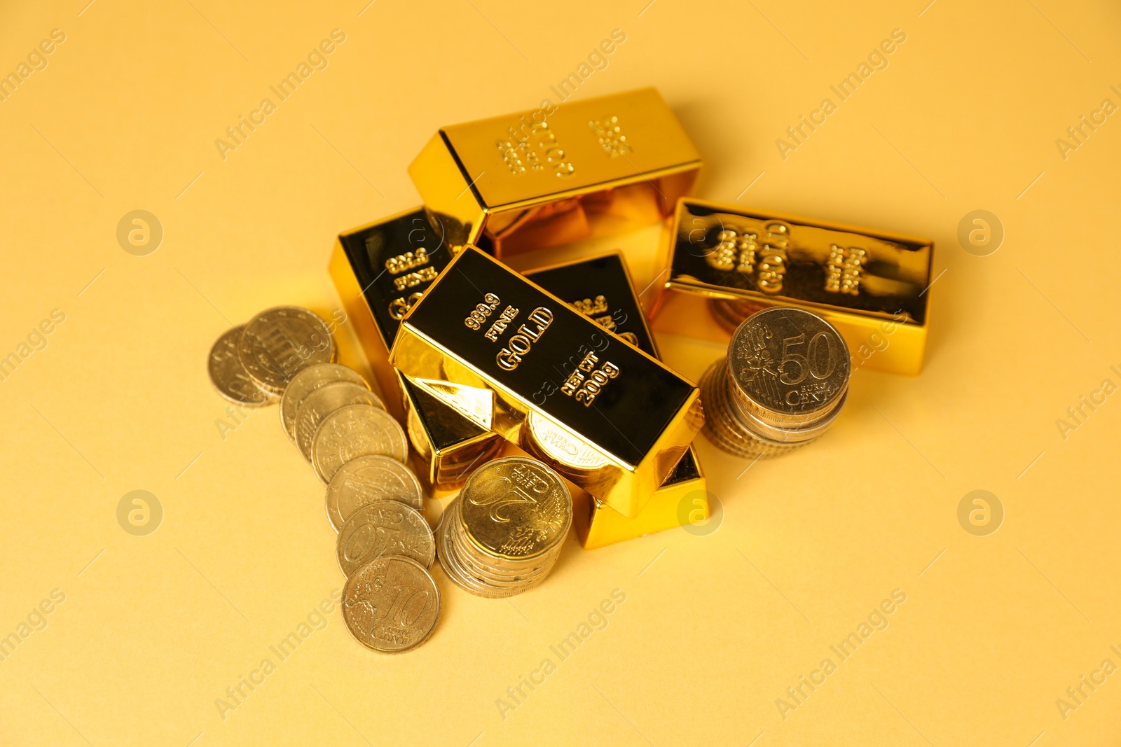 Photo of Gold bars and coins on golden background, above view