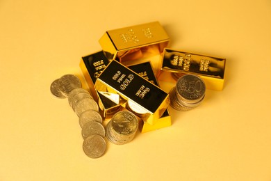 Photo of Gold bars and coins on golden background, above view