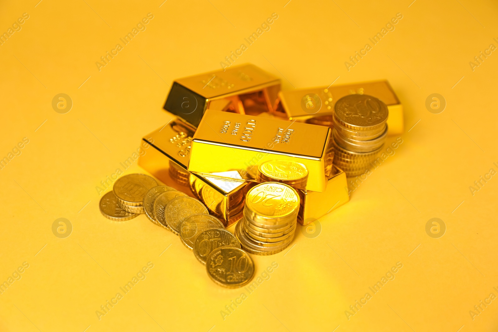 Photo of Gold bars and coins on golden background, closeup