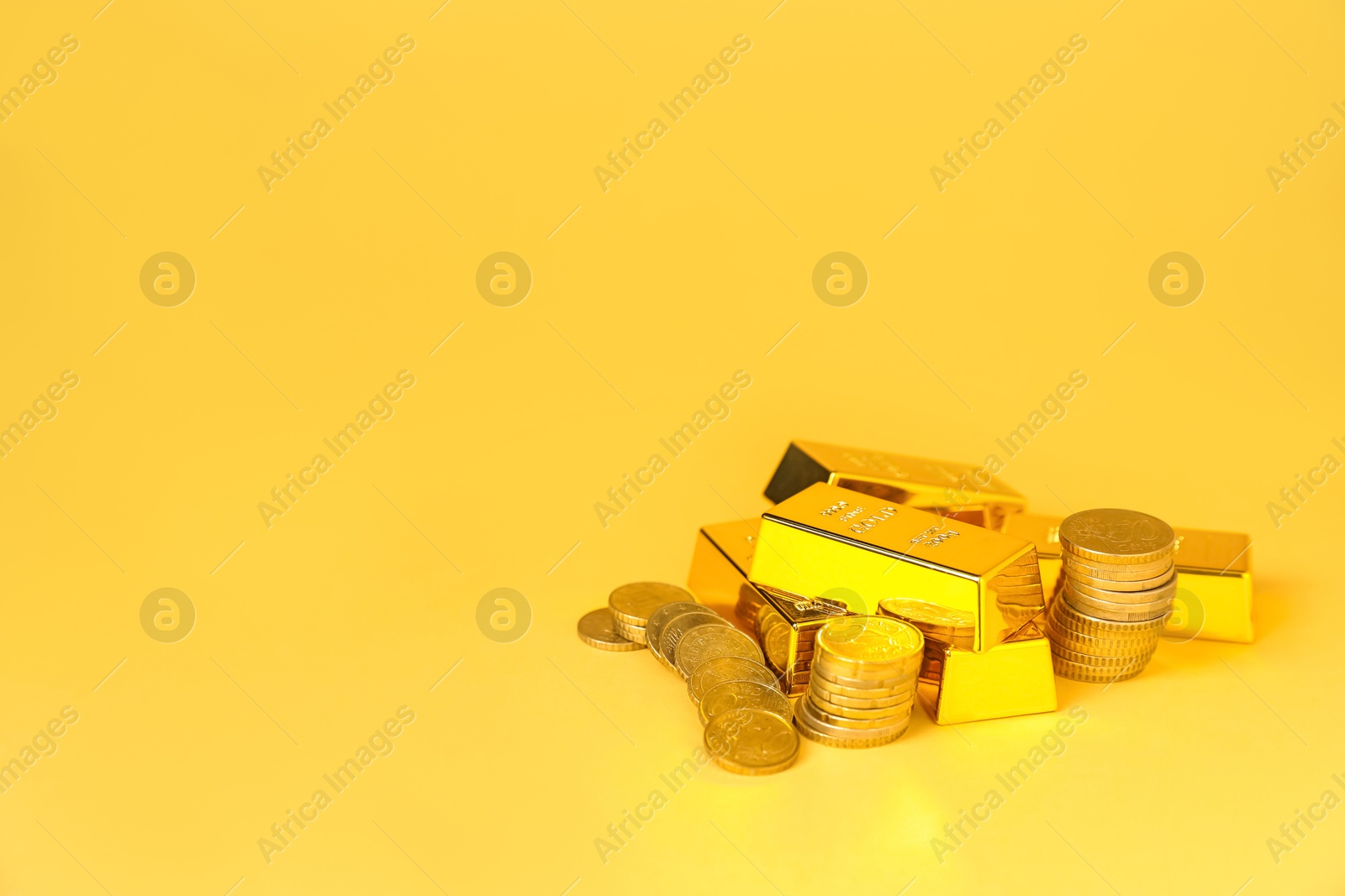 Photo of Gold bars and coins on golden background, space for text