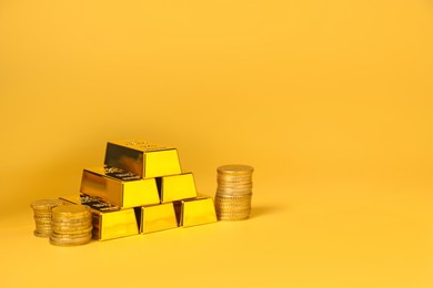 Photo of Gold bars and coins on golden background, space for text