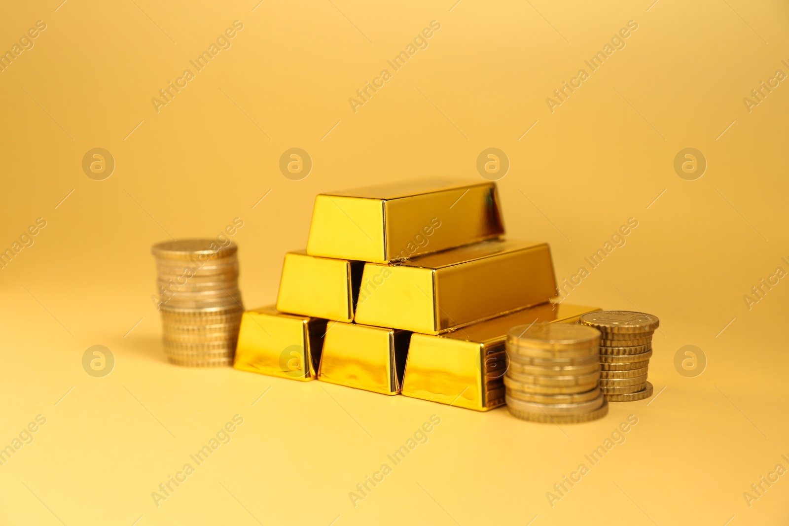 Photo of Gold bars and coins on golden background, closeup