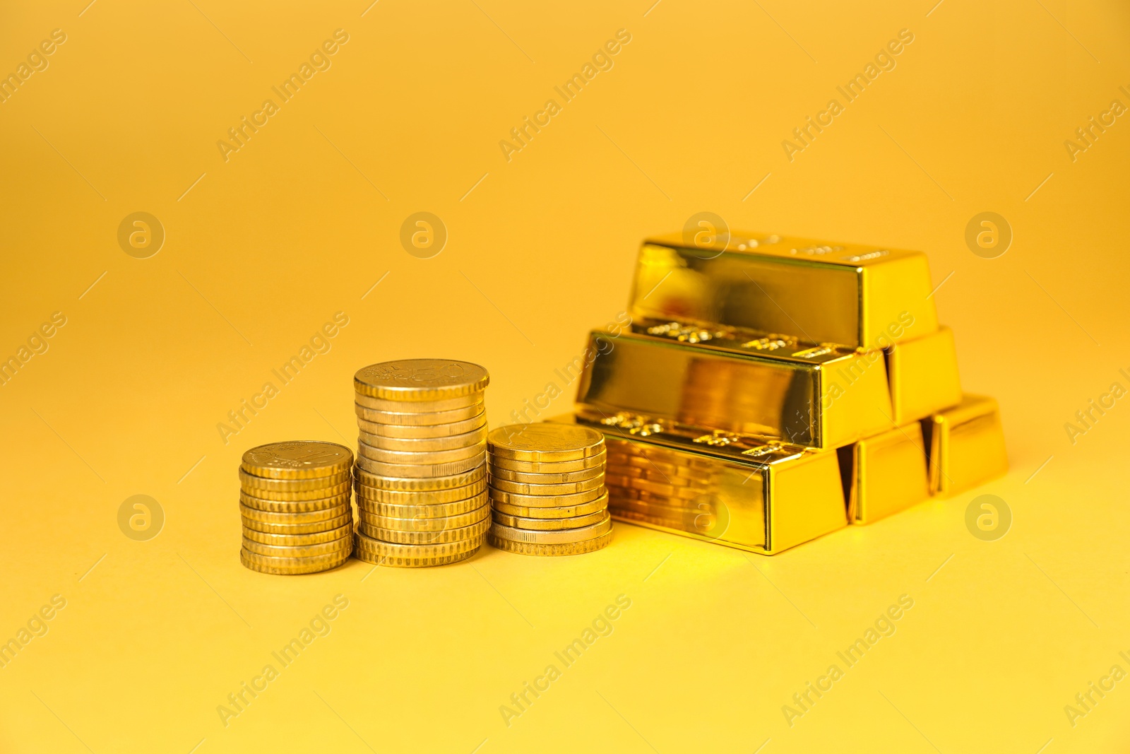 Photo of Gold bars and coins on golden background, closeup