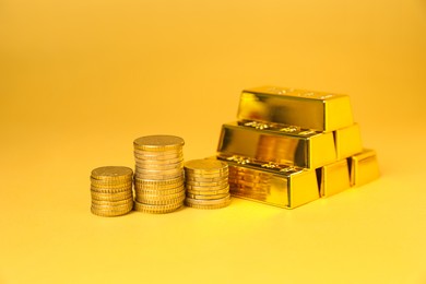 Photo of Gold bars and coins on golden background, closeup