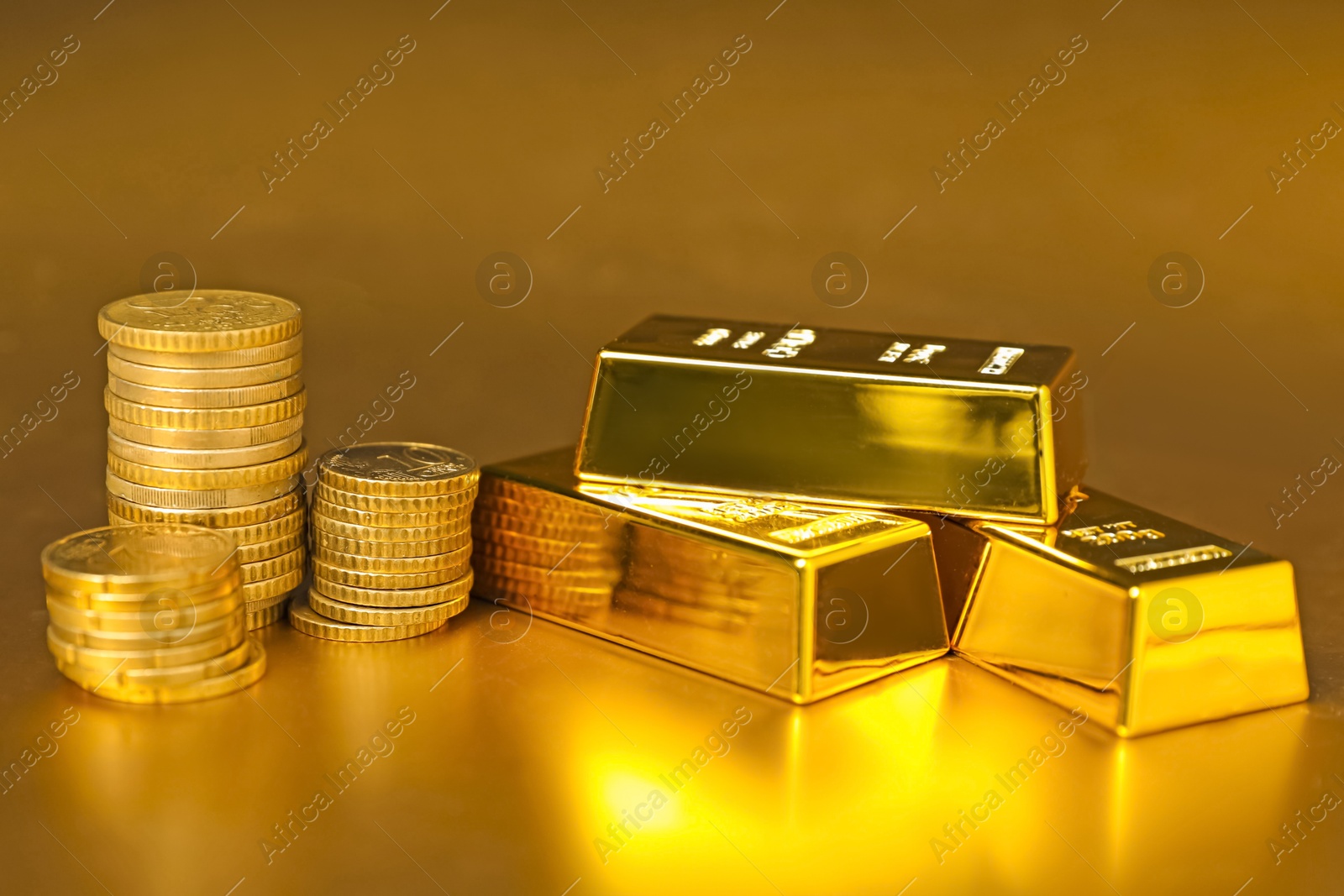 Photo of Gold bars and coins on shiny background, closeup