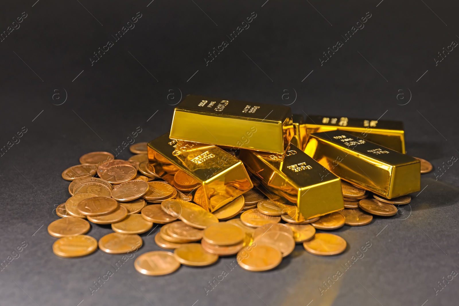 Photo of Gold bars and coins on black table, closeup