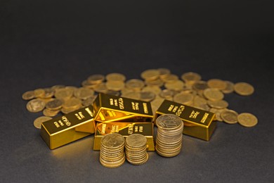 Photo of Gold bars and coins on black table, closeup