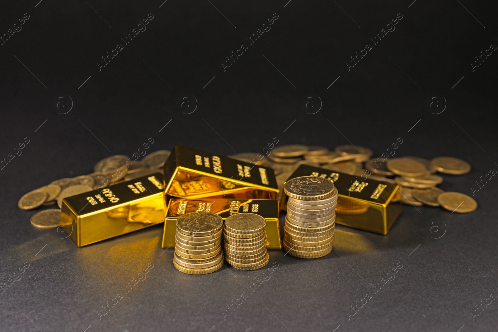 Photo of Gold bars and coins on black table, closeup