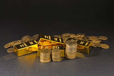 Photo of Gold bars and coins on black table, closeup