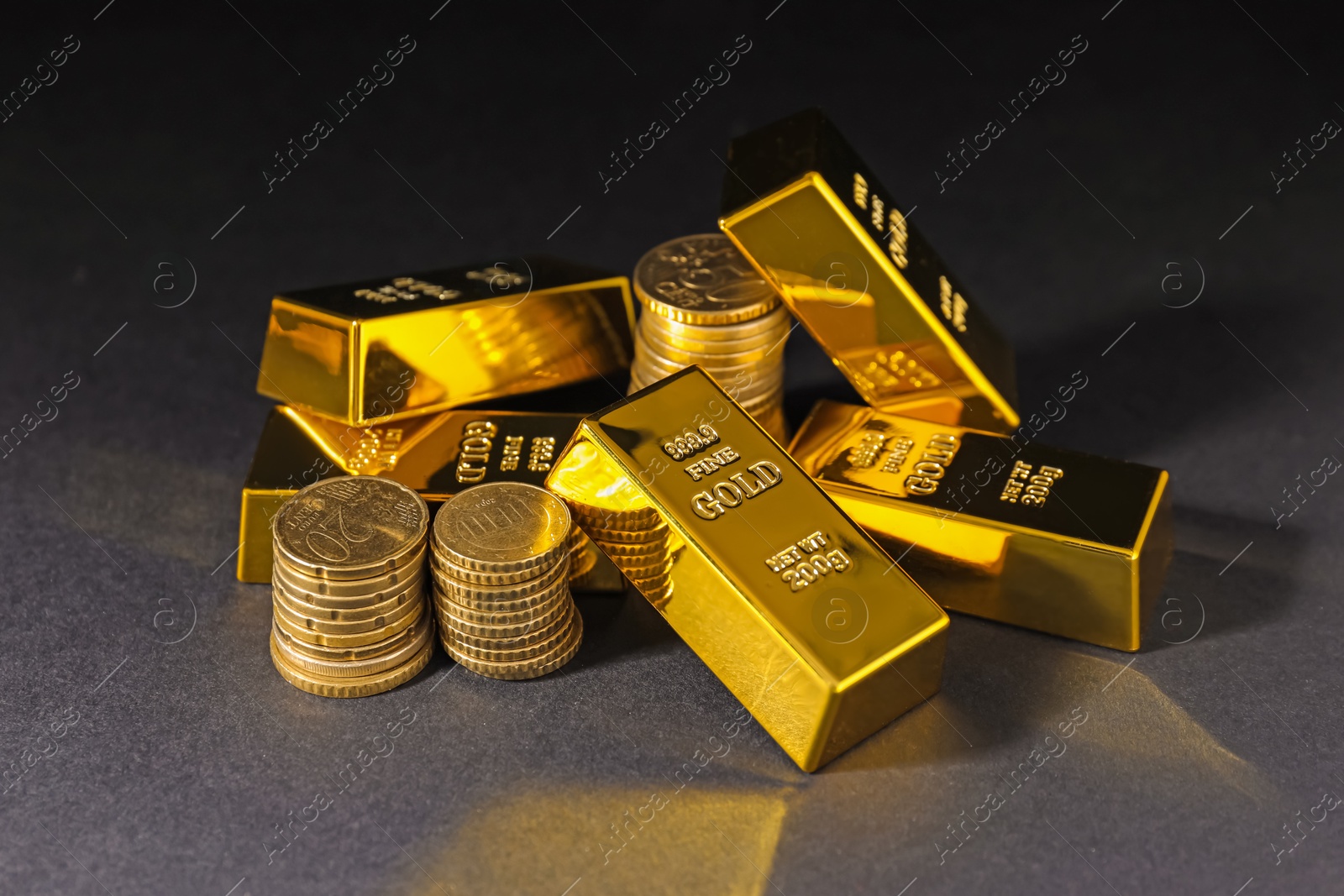 Photo of Gold bars and coins on black table, closeup