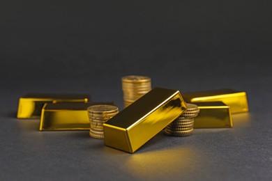 Photo of Gold bars and coins on black table, closeup