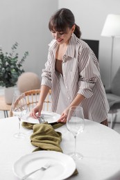 Photo of Woman setting table for dinner at home