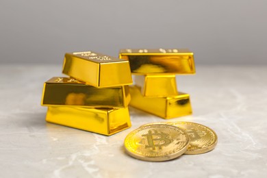 Photo of Gold bars and coins on grey marble table, closeup