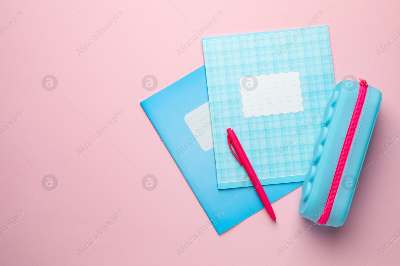 Photo of Copybooks, pen and pencil case on pink background, flat lay. Space for text