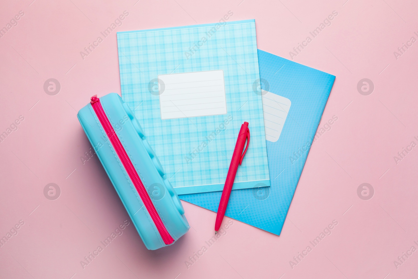 Photo of Copybooks, pen and pencil case on pink background, flat lay