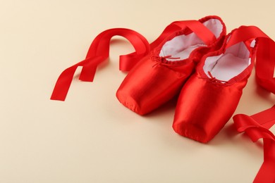 Photo of Pair of red pointe shoes on beige background. Space for text