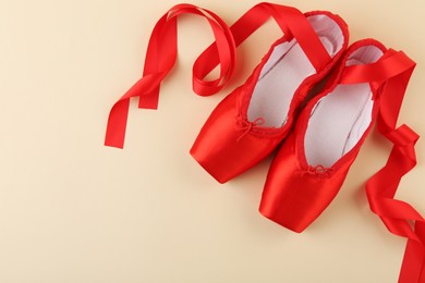 Photo of Pair of red pointe shoes on beige background, top view. Space for text