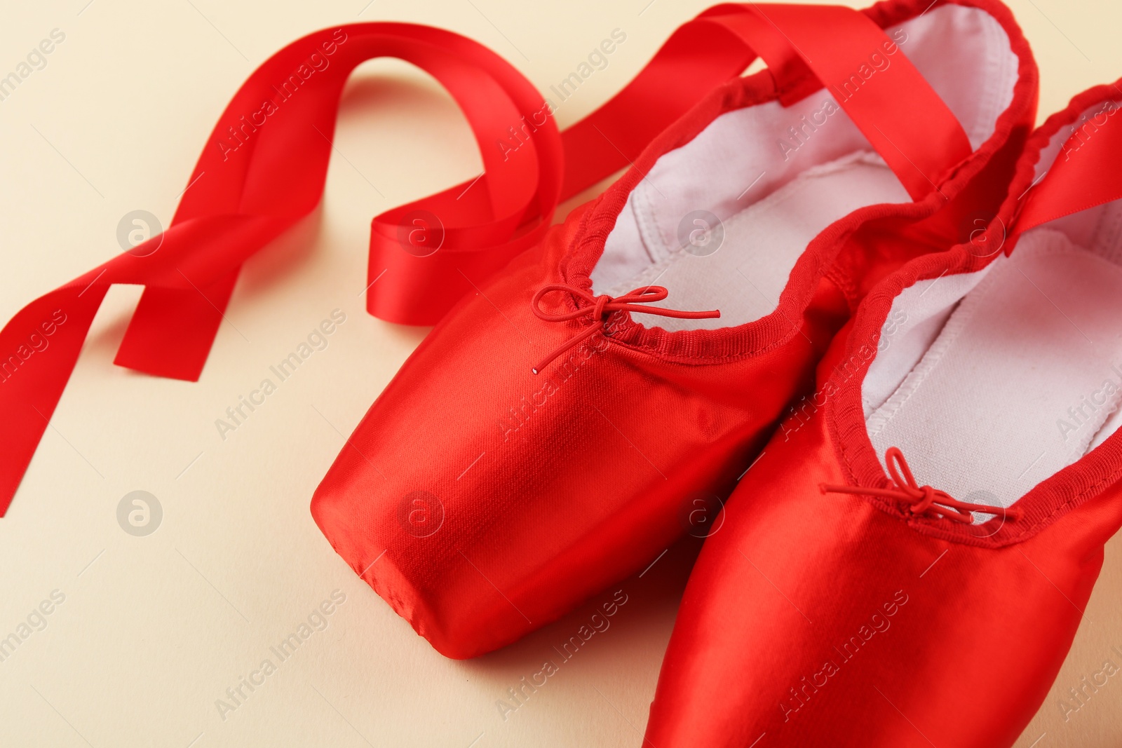 Photo of Pair of red pointe shoes on beige background, closeup