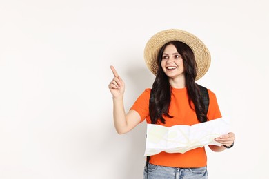 Photo of Young tourist in hat with map pointing at something on white background, space for text