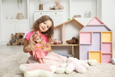 Photo of Cute little girl playing with her doll at home