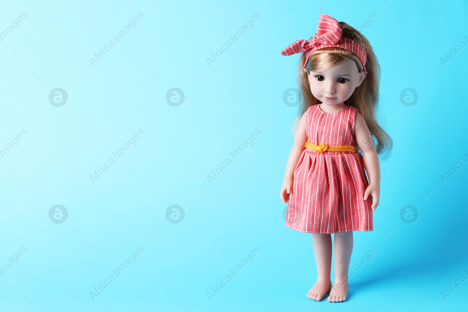 Photo of Beautiful doll in dress and headband on light blue background. Space for text