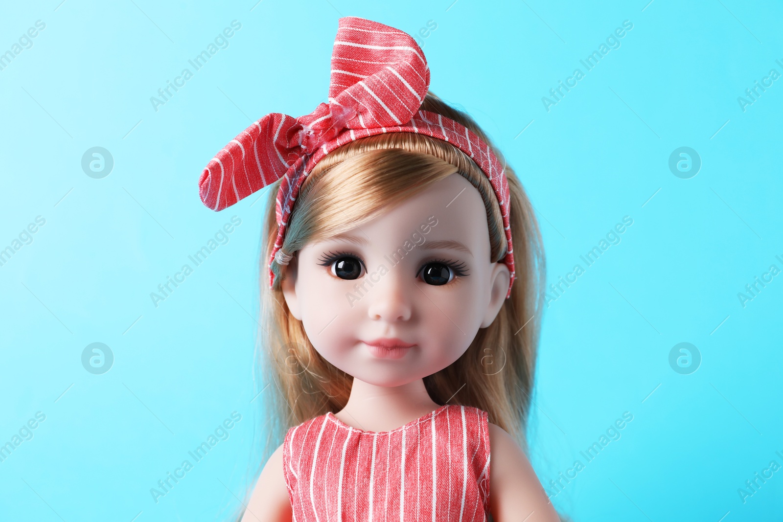 Photo of Beautiful doll with headband on light blue background, closeup