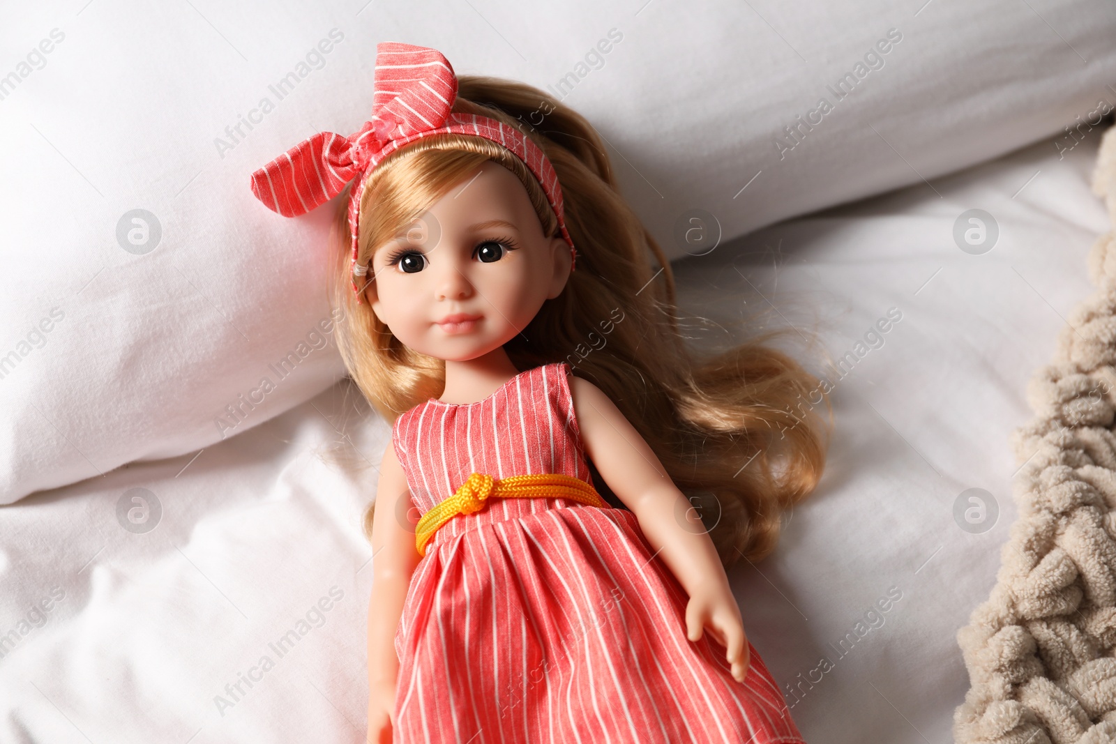 Photo of Beautiful doll in dress and headband on bed