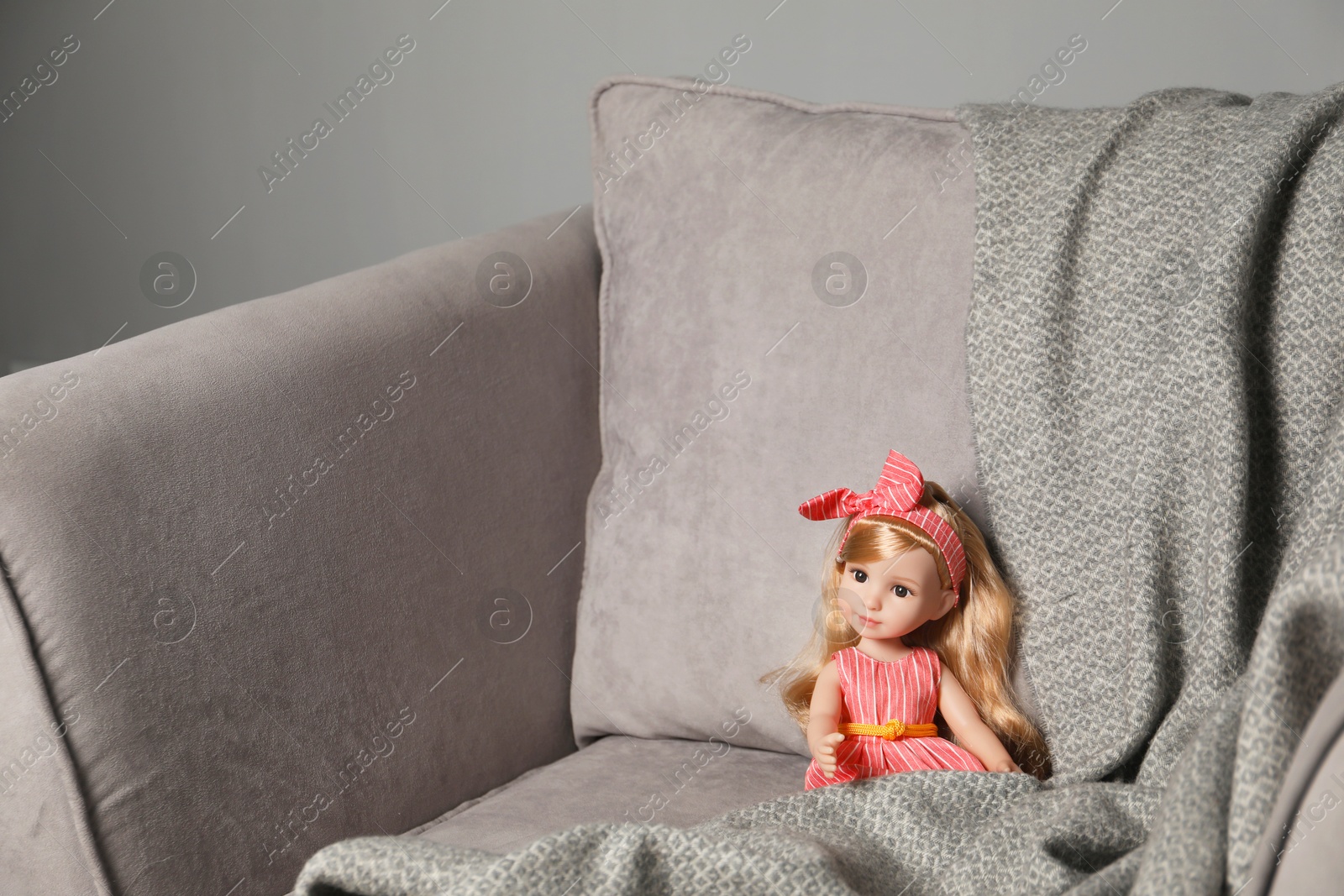 Photo of Beautiful doll and blanket in soft armchair. Space for text