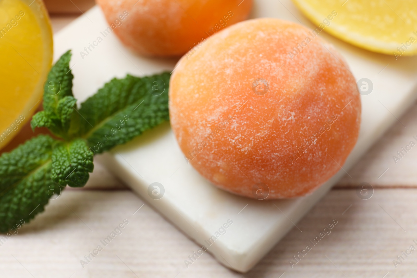 Photo of Delicious mochi, lemons and mint on wooden table, closeup