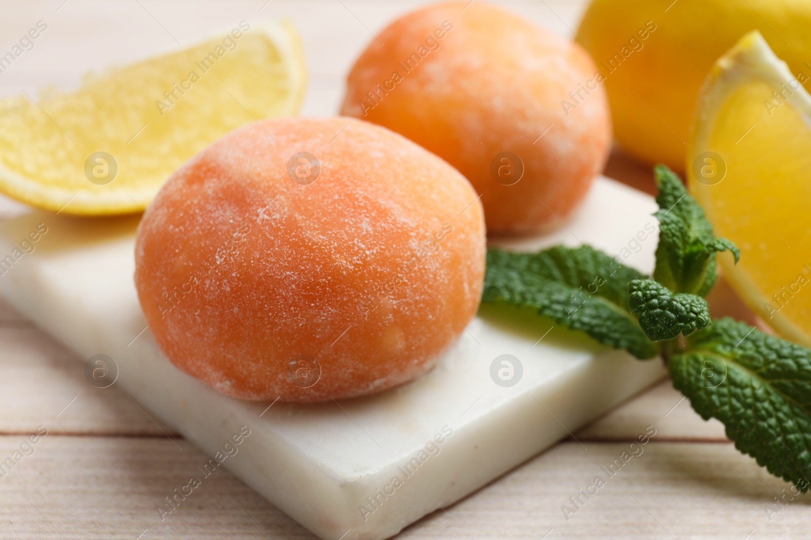 Photo of Delicious mochi, lemons and mint on wooden table, closeup