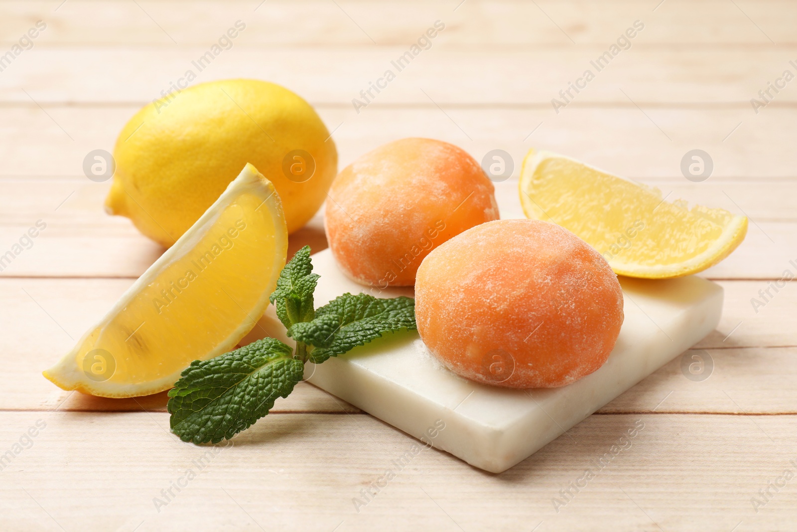 Photo of Delicious mochi, lemons and mint on wooden table, closeup