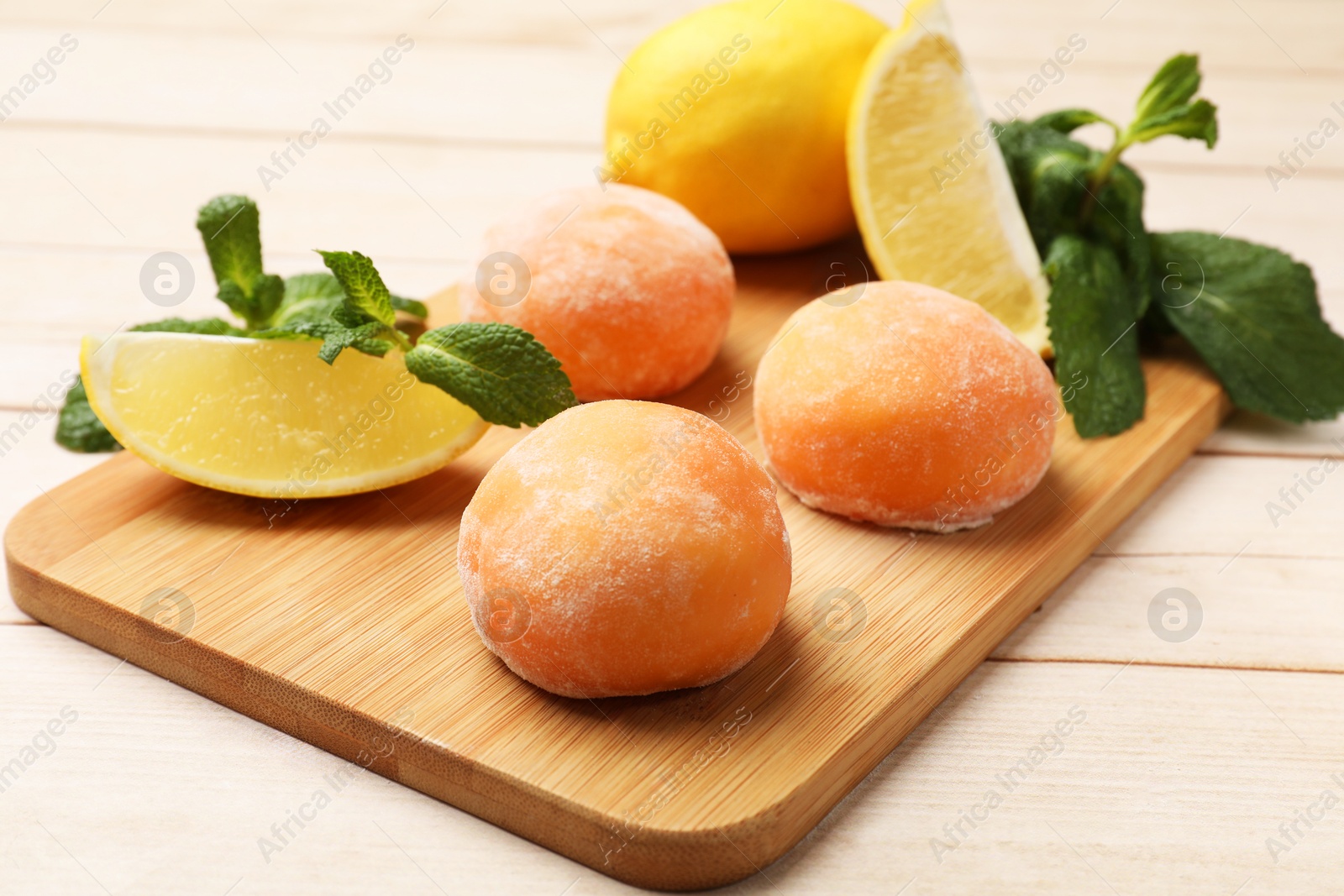 Photo of Delicious mochi, lemons and mint on wooden table, closeup