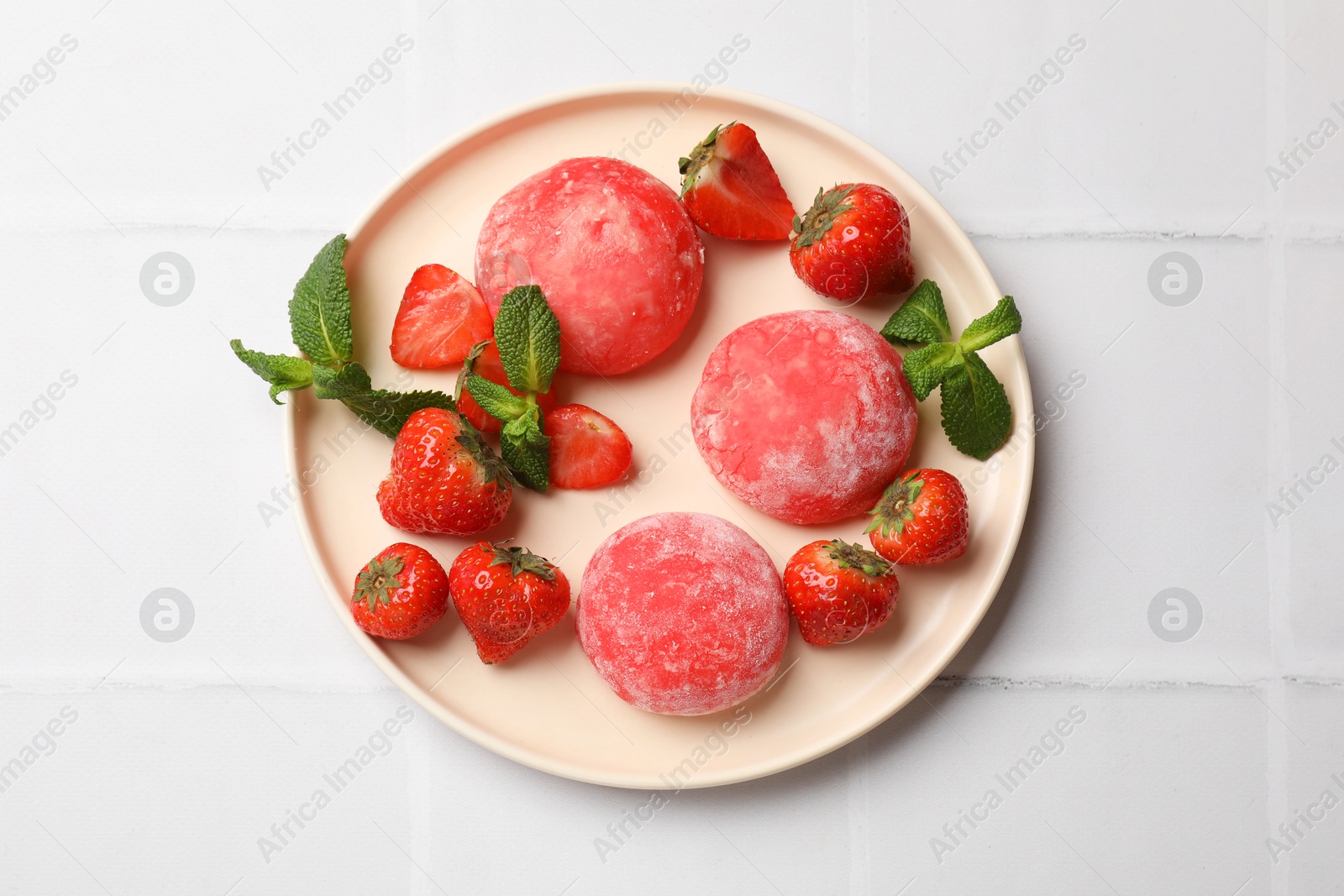 Photo of Delicious mochi, strawberries and mint on white tiled table, top view