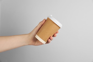 Photo of Woman holding paper cup on grey background, closeup. Mockup for design