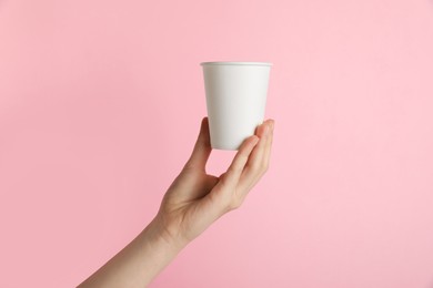 Photo of Woman holding paper cup on pink background, closeup. Mockup for design