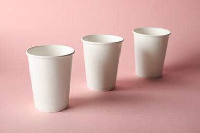 Photo of Paper cups on pink background, closeup. Mockup for design