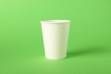 Photo of One paper cup on green background. Mockup for design